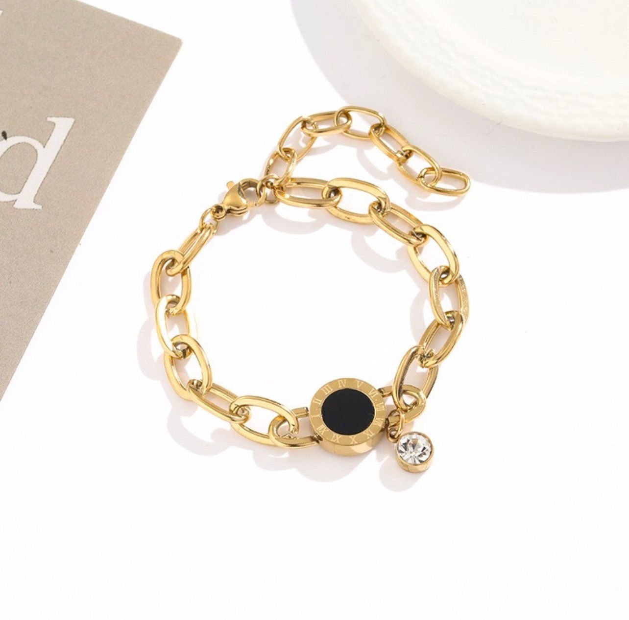 18K Gold-Plated bracelet featuring round charm with black inlay and Roman numerals, and a dangling zircon stone
