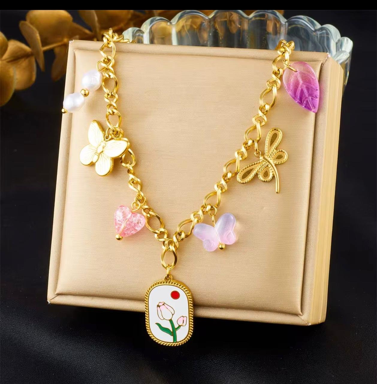 18K Gold-Plated necklace with a central elliptical pendant with an enameled tulip and a red sun motif surrounded with several smaller charms