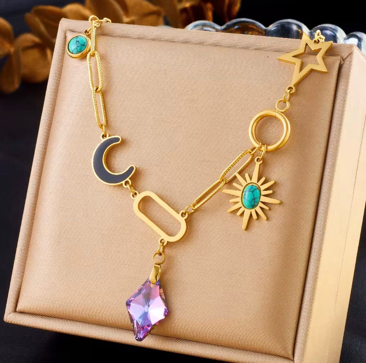 18K Gold-Plated celestial multi-charm necklace with a purple crystal pendant, turquoise stones, a moon, a sun, and a star