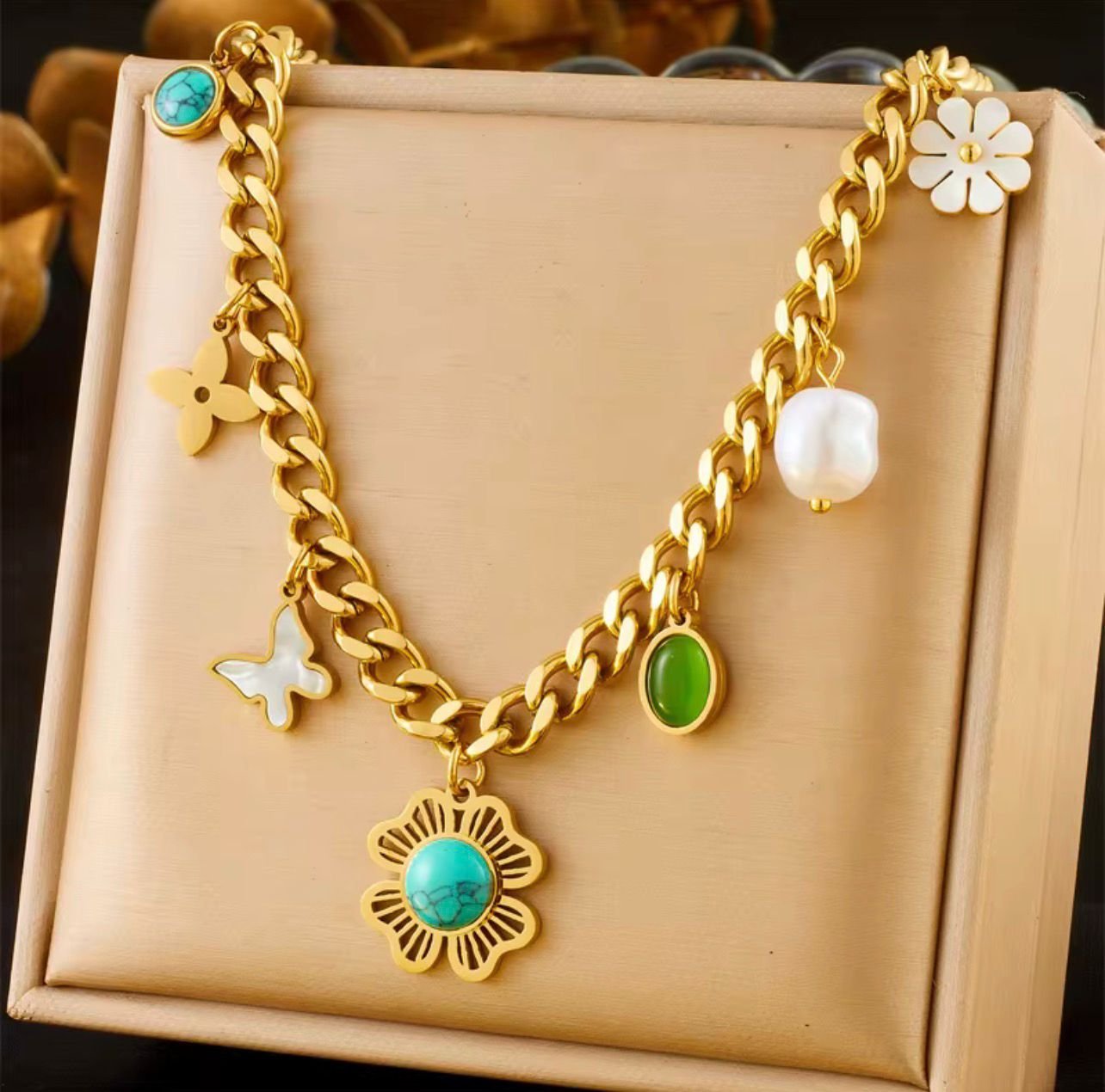 18K Gold-Plated trendy necklace featuring a chunky chain and various charms including a turquoise flower, pearl, butterfly, and green stone