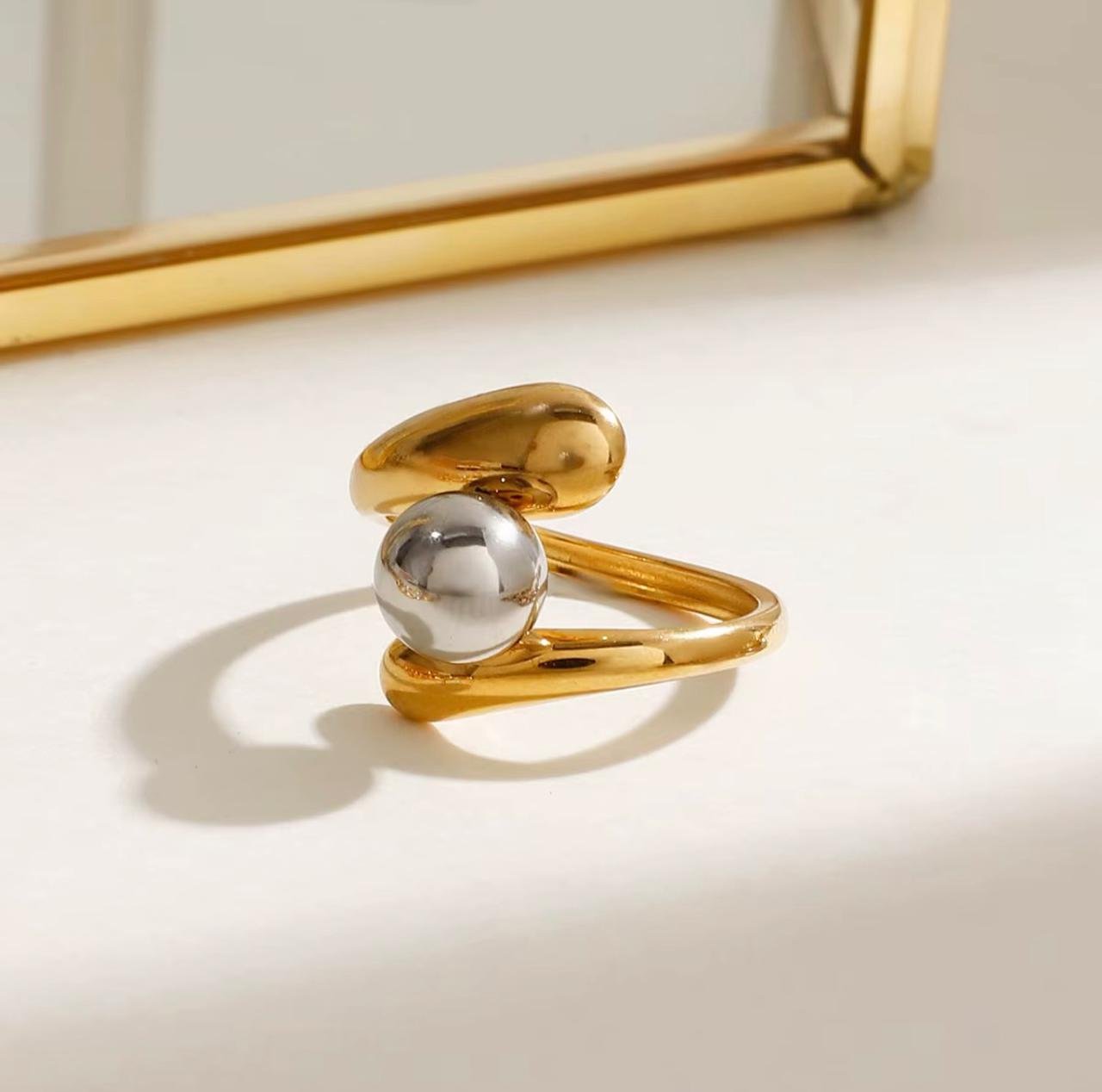 18K Gold-Plated sculptural ring it is resizable and it features a modern, asymmetrical bypass design with a polished silver-toned pearl that appears to "float" within a thick bypass band