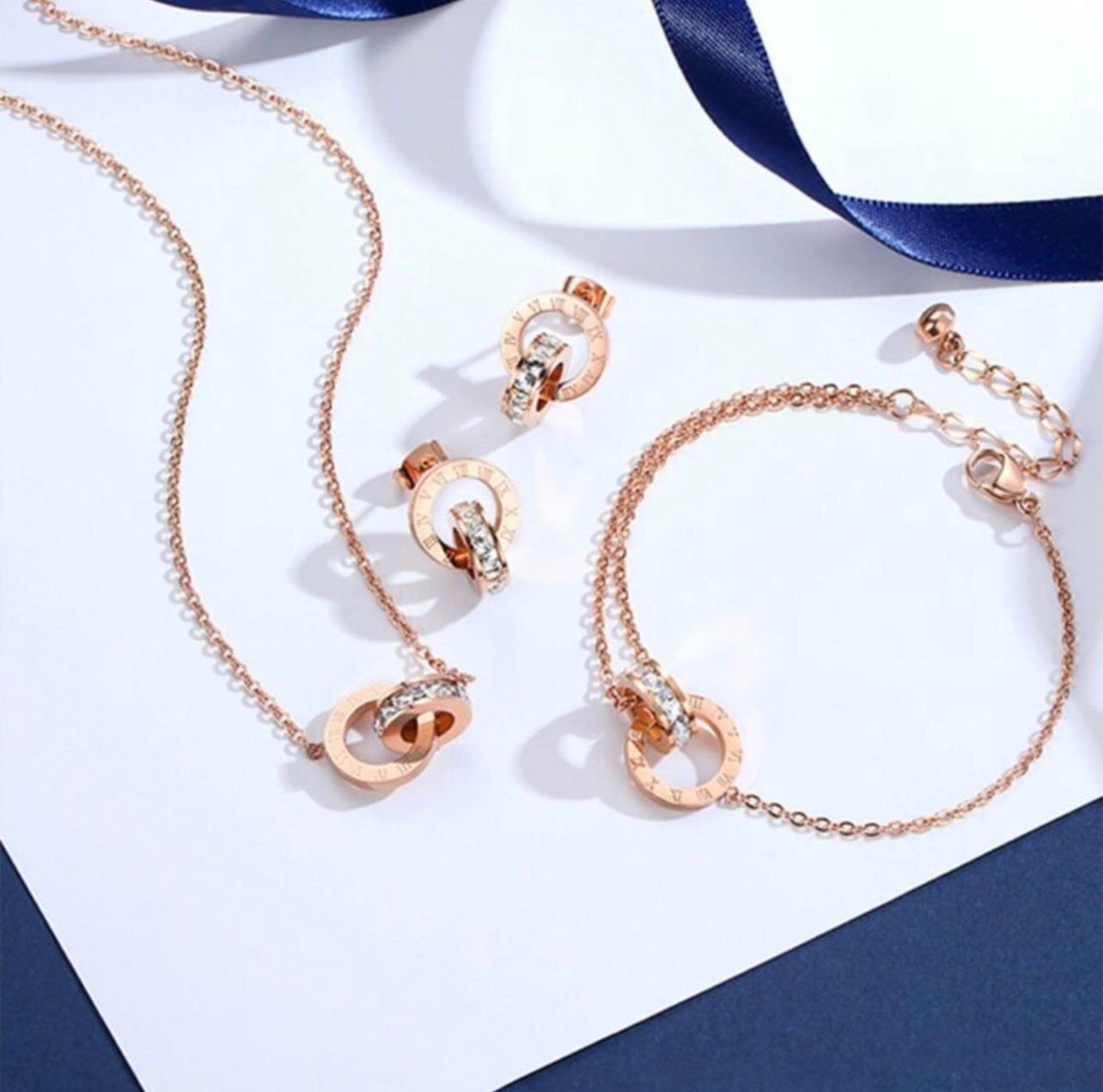 18K rose gold-plated Roman numeral double-loop jewelry set including a necklace, bracelet, and earrings