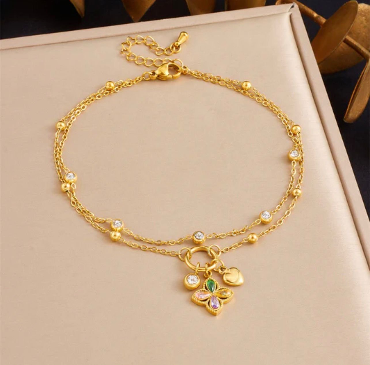 stainless steel anklet features colorful zircon inlay in a four-leaf flower design and a heart pendant